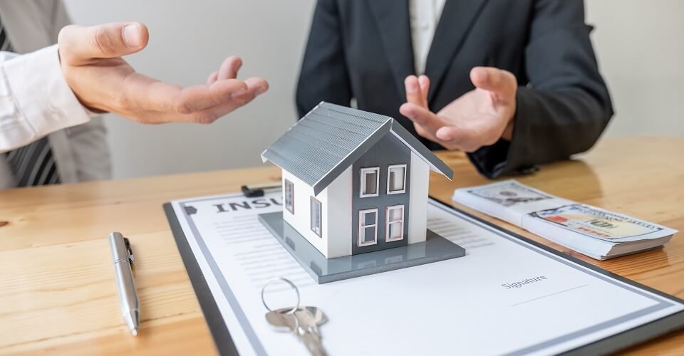 2 people talking near a model of a house